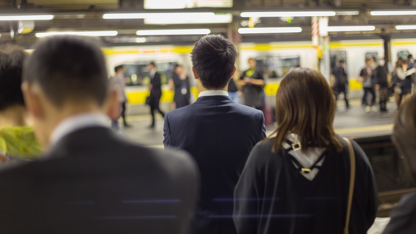 Passengers traveling by Tokyo metro. Business people commuting to work by public transport in rush hour. Shallow depth of field photo.