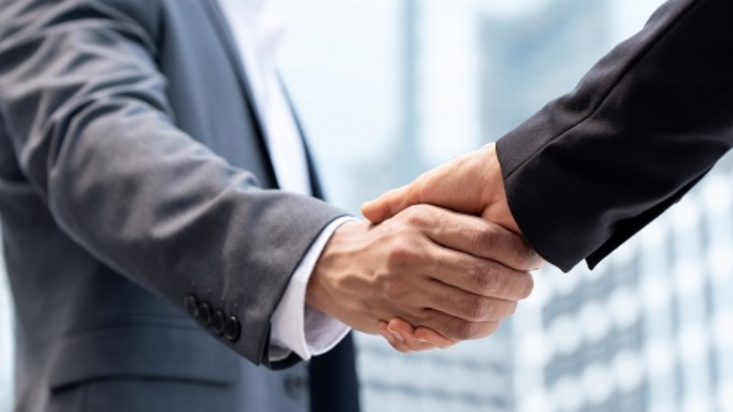 Businessmen making handshake outdoors in city office building background for merger and acquisition concept