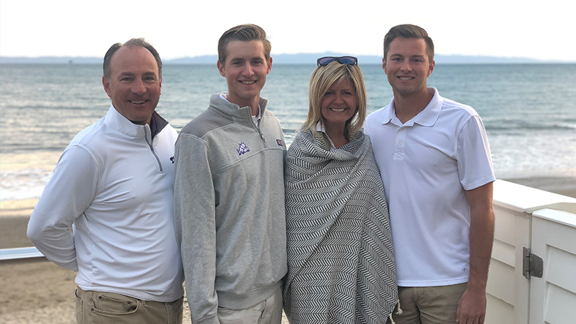 Bazarevitsch family of four standing, smiling in front of the ocean and beach.